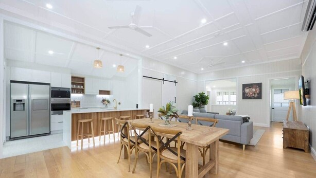 A modern kitchen with a central island, wooden dining table, and bar stools. - Grand 4BR Queenslander on Harold – Sleeps 7 (West End)