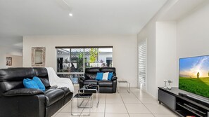 Ein modernes Wohnzimmer mit einem schwarzen Ledersofa, einem Couchtisch und einem Flachbildfernseher.