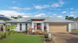 A modern two-story house with a garage, solar panels, and a well-maintained lawn. - Waterlily Oasis Stylish 4 Bedroom Stay (Douglas)
