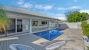 Una casa moderna con piscina, mobiliario exterior y cielo despejado.