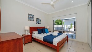 Ein Schlafzimmer mit Bett, Nachttischen, Schreibtisch, Deckenventilator und einem Fenster mit Blick.