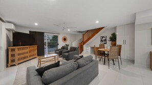 Una sala de estar moderna con un sofá, sillas, una mesa de comedor y una escalera.