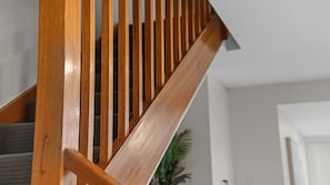 A wooden staircase with a handrail and a carpeted landing. - Coastal Comfort Near The Strand (North Ward)