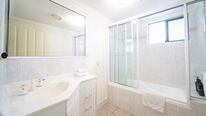 Ein modernes Badezimmer mit Waschbecken, Spiegel und einer Duschkabine.