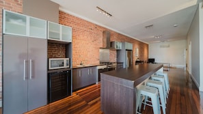 Eine moderne Küche mit Backsteinwand, Edelstahlgeräten und Holzboden.
