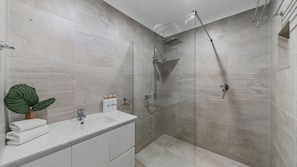 Un baño moderno con ducha, lavamanos y una planta.