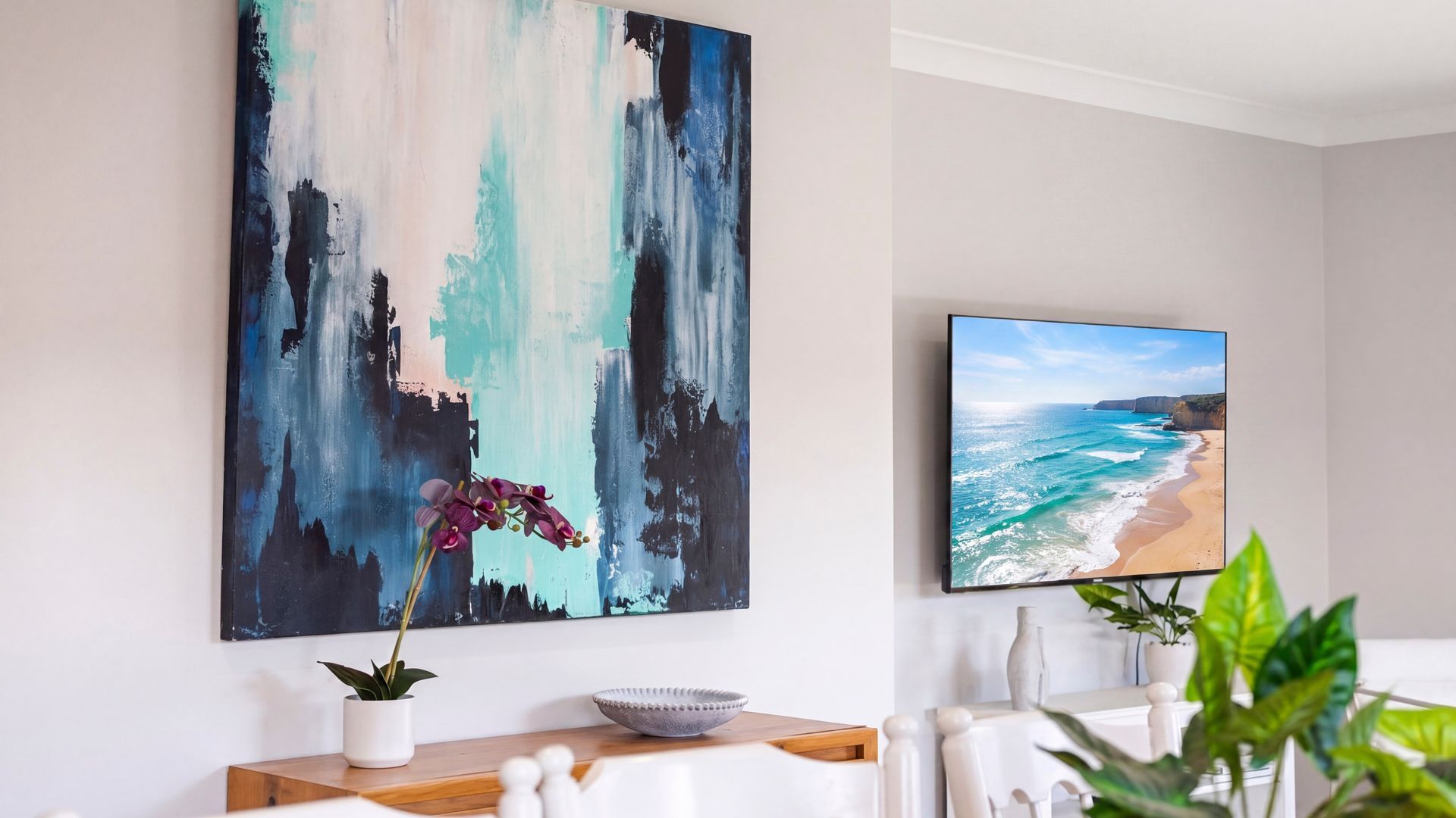 A dining area with a table, chairs, a vase with flowers, and two wall-mounted artworks.