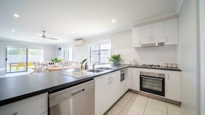 A modern kitchen with white cabinets, a dishwasher, a stove, and a sink. - The Northside Haven (Burdell)
