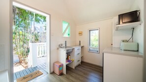A compact kitchen with a sink, countertop, and a microwave on a shelf. - Palm Grove Cottage and Private Studio (South Townsville)