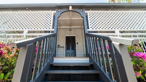 A staircase leading to a door with a lattice fence on either side. - Palm Grove Cottage and Private Studio (South Townsville)