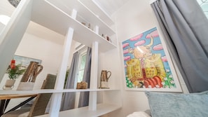 A room with white shelving, a painting of a bull, and a grey curtain. - Palm Grove Cottage and Private Studio (South Townsville)