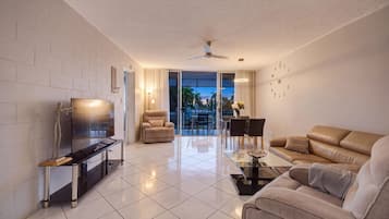 A modern living room with a flat-screen TV, leather sofa, and a dining area with a glass table.