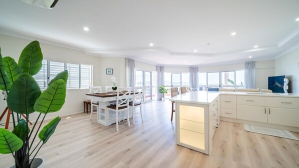 A spacious living area with a dining table, chairs, and a kitchen island with cabinets.