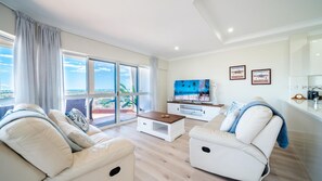 A modern living room with a sofa, a coffee table, and a TV.