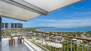 Un balcone con vista su un paesaggio costiero, che include una spiaggia e montagne in lontananza.