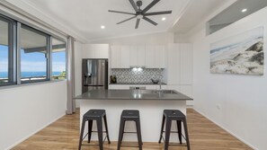 A modern kitchen with a large island, stainless steel appliances, and a view of the sea. - Searenity on Castle hill (Castle Hill)