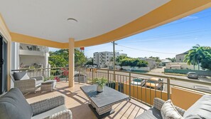 A balcony with outdoor furniture, a view of a street, and buildings in the background. - Seaside Stays North Ward (North Ward)
