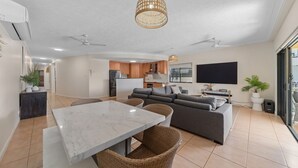 Ein modernes Wohnzimmer mit einem Marmortisch, einem grauen Sofa und Korbstühlen.