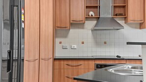 Een moderne keuken met houten kastjes, een roestvrijstalen afzuigkap en een inbouwvaatwasser.