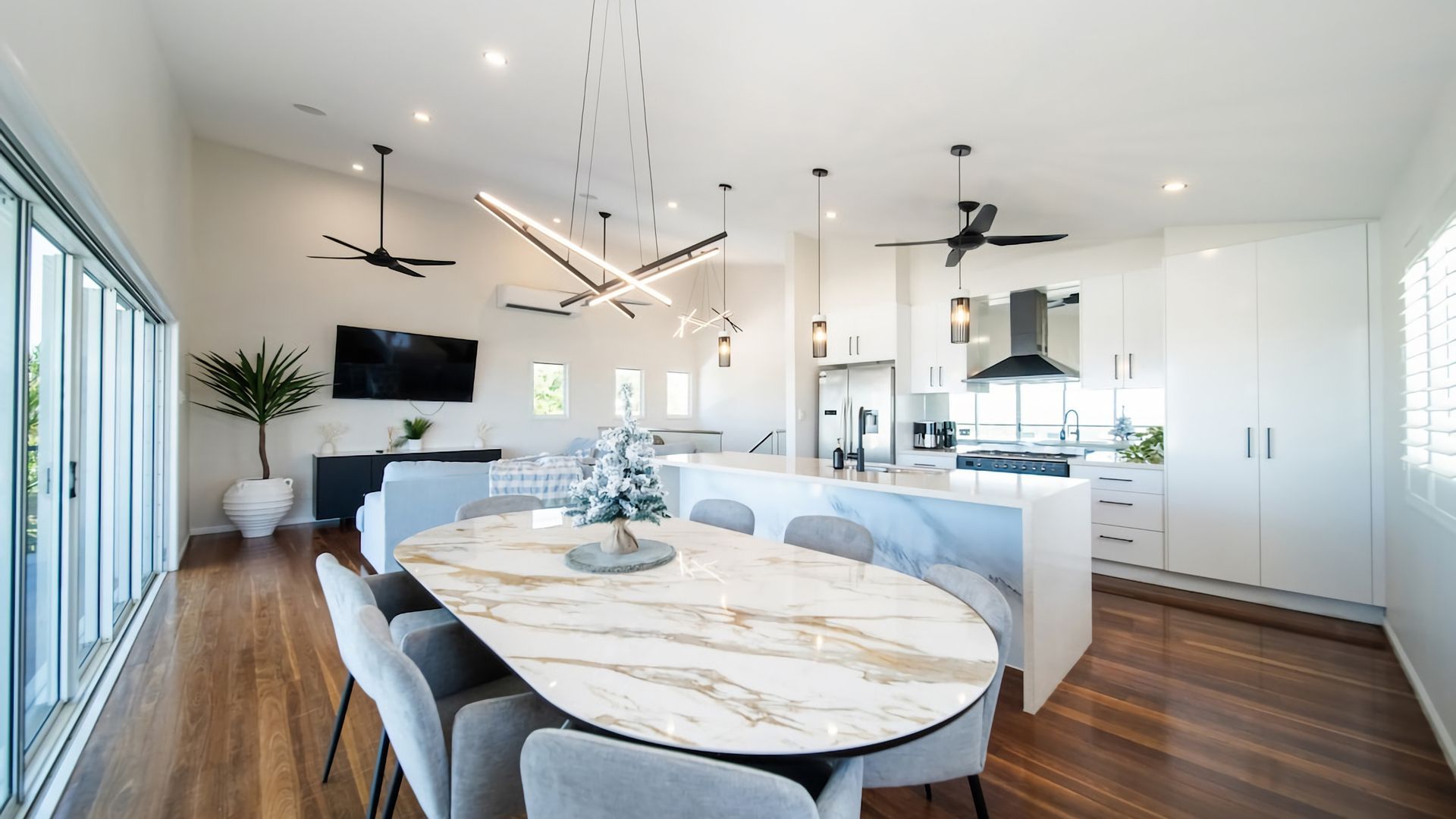 A modern kitchen with a marble island, built-in appliances, and pendant lighting.