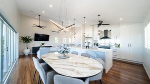 A modern kitchen with a marble island, built-in appliances, and pendant lighting. - Executive Coastal Living with Ocean Views (Bushland Beach)