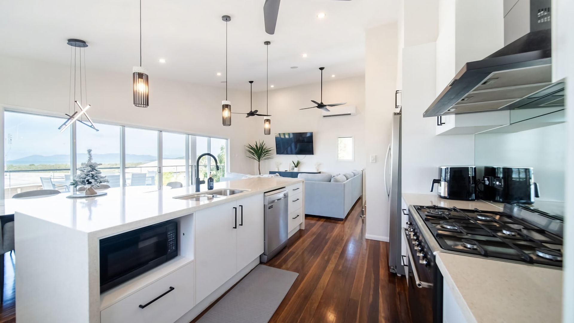 A modern kitchen with a central island, built-in appliances, and a view to the outside.