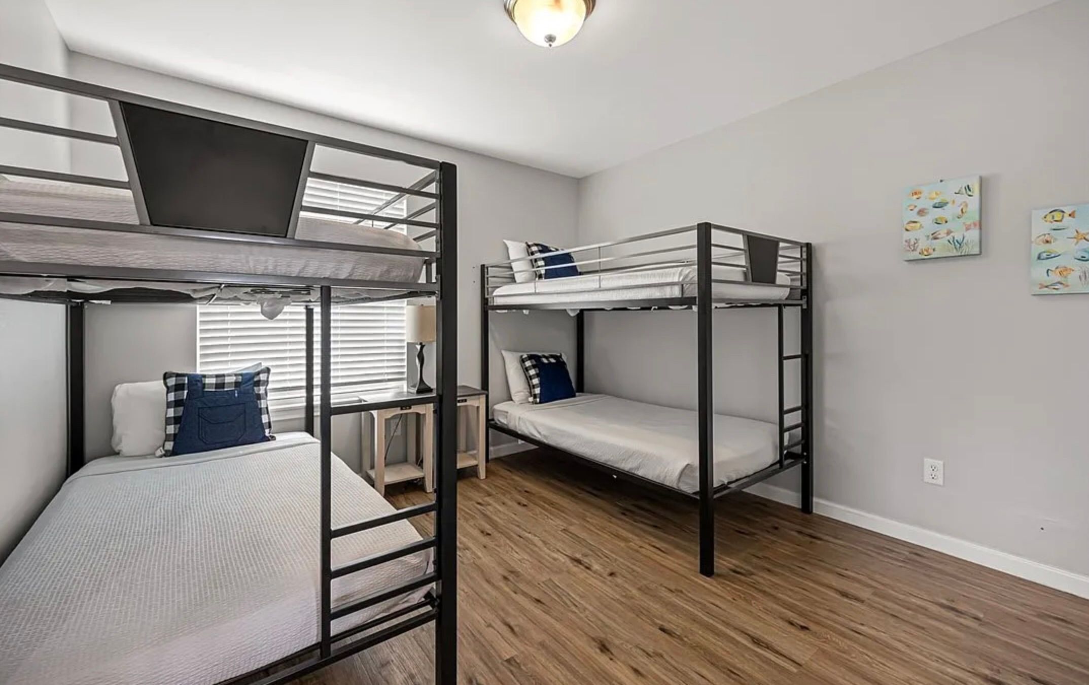 A dormitory room with bunk beds, a desk, and a window with blinds.
