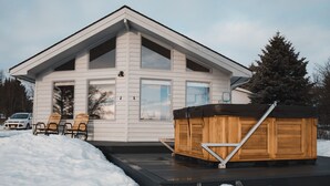 A modern house with a hot tub on the deck, surrounded by snow. - Shorebird Cottage (Homer)