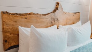 A bed with white pillows and a wooden headboard against a white wall. - Shorebird Cottage (Homer)