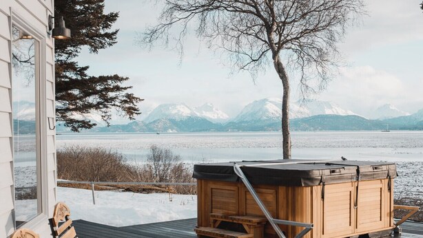 A wooden deck with two wooden chairs and a hot tub. - Shorebird Cottage (Homer)