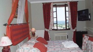 A bedroom with a bed, a window, a television, and an air conditioning unit. - Le Logis du Guetteur (Les Arcs-sur-Argens)