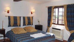 A bedroom with a bed, two wall-mounted lamps, a window with curtains, and an air conditioning unit. - Le Logis du Guetteur (Les Arcs-sur-Argens)