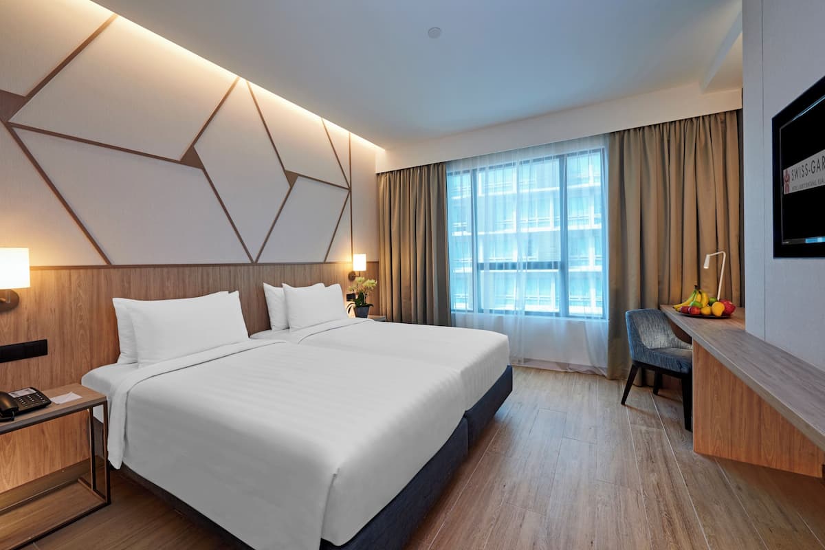 Ein modernes Hotelzimmer mit einem großen Bett, einem Schreibtisch mit Computer und einem großen Fenster mit Vorhängen.