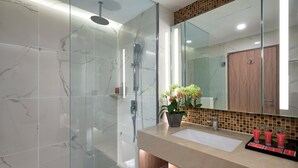 A modern bathroom with a glass-enclosed shower, a marble-tiled wall, a wooden vanity, and a large mirror. - Grand Mercure Kuala Lumpur Bukit Bintang (Kuala Lumpur)