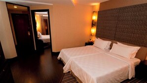 A hotel room with a large bed, a nightstand, and a wall-mounted light fixture. - Grand Mercure Kuala Lumpur Bukit Bintang (Kuala Lumpur)