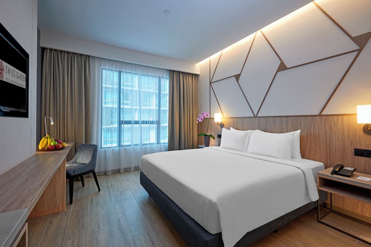 Ein modernes Hotelzimmer mit einem großen Bett, einem Schreibtisch, einem Stuhl und einem fensterbepflanzten Fenster.