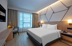 Una moderna camera d'albergo con un letto grande, una scrivania, una sedia e una finestra con tende.