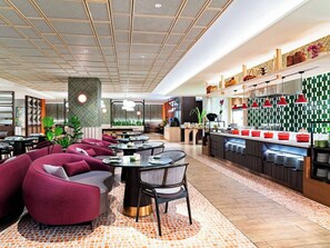 Un restaurante moderno con un área de comedor central, una barra y una cocina a la vista.