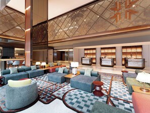 Una hall moderna con zone relax, una reception e un bar.