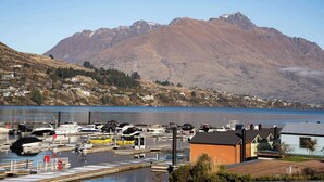 A marina with boats docked, a small building, and a mountainous backdrop. - Family-Friendly 3BR Marina Views & Space (Queenstown)