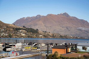 A marina with boats docked, a small building, and a mountainous backdrop. - Family-Friendly 3BR Marina Views & Space (Queenstown)