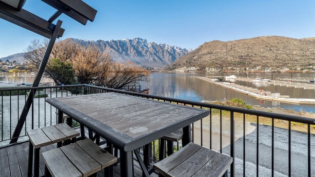 A wooden deck with benches overlooking a lake and mountains. - Family-Friendly 3BR Marina Views & Space (Queenstown)