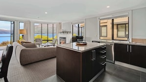 A modern kitchen with dark cabinetry, a central island, and a view of the outdoors. - Lakefront Apartment , 2 Bed, Central, walk to town (Queenstown)
