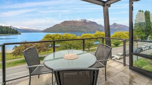 A glass table with four chairs on a balcony overlooking a lake and mountains. - Gorgeous Lakefront, 3 Bed apartment, walk to town (Queenstown)