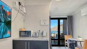 Eine kompakte Küche mit Mikrowelle, Toaster und Wasserkocher, ein kleiner Essbereich mit Tisch und Stühlen sowie ein Balkon mit schöner Aussicht.