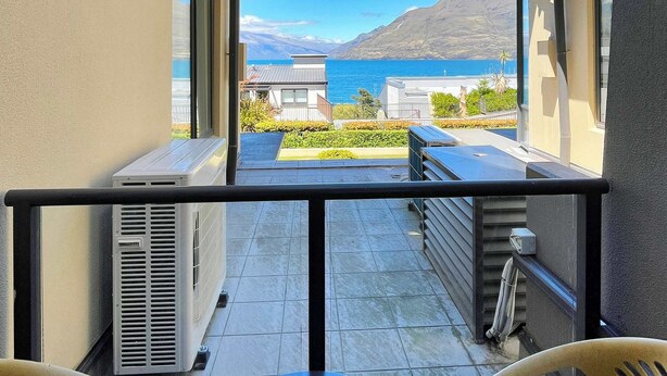 Ein Balkon mit Blick auf das Meer und die Berge, ausgestattet mit einem Tisch und Stühlen.