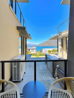 A balcony with a view of the sea and mountains, featuring a table and chairs. - Lakefront Central Studio, walk to town! (Queenstown)