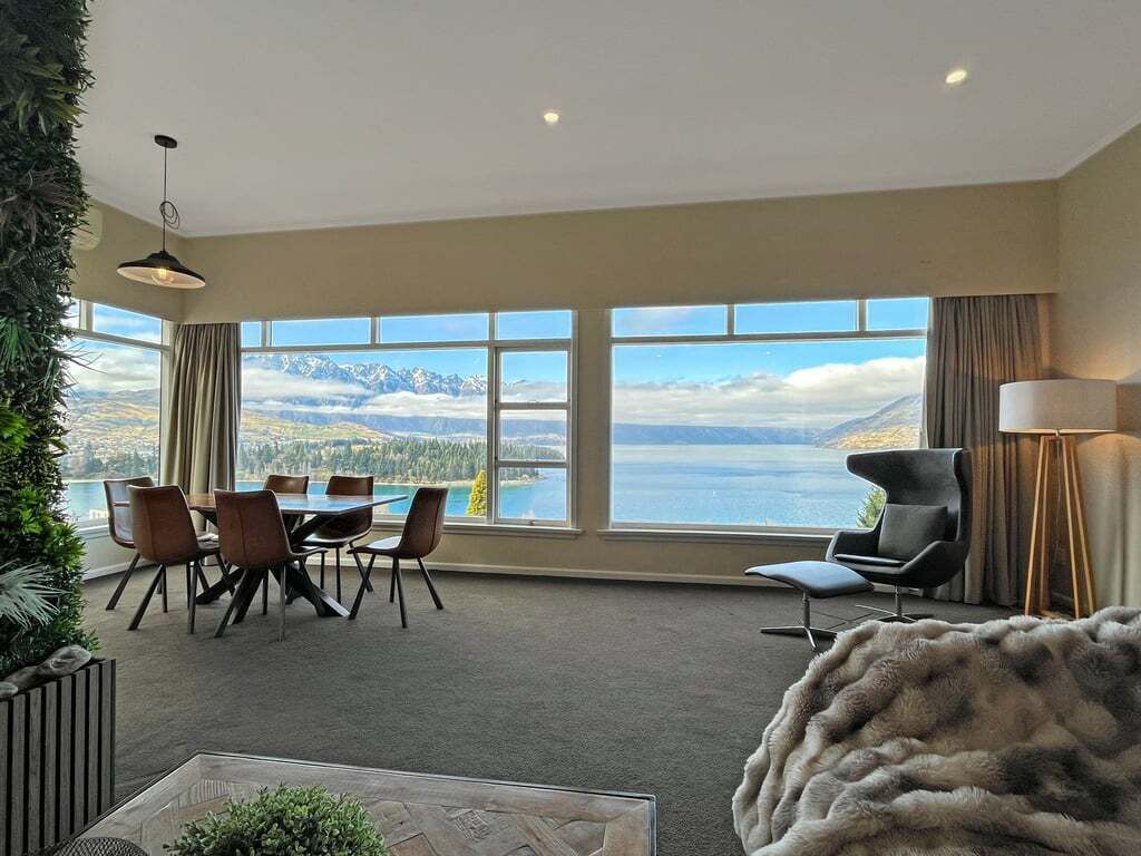 A spacious room with a large dining table, chairs, and a view of mountains and a lake.
