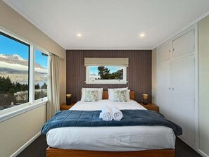A bedroom with a large bed, a window with a view of a mountain, and a wardrobe. - The Biggest & Best Views, 3 Bedrooms, Walk To Town (Queenstown)