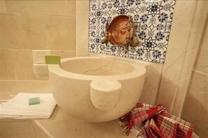 A bathroom with a large, white ceramic toilet bowl, a patterned tile backsplash, and a green sponge on a white towel. - Tunel Residence (Istanbul)